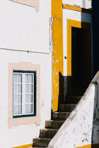 A vertical shot of a concrete staircase along a building with a window under sunlight in Portugal