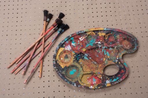 A closeup shot of paint brushes and a color mixing plate