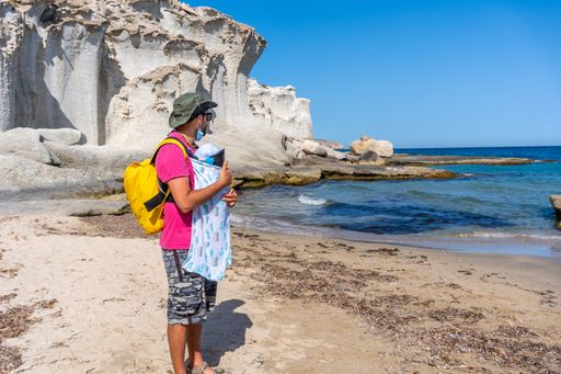 A young father with his newborn son walking along the shore in Enmedio beach in Almeria, Spain
