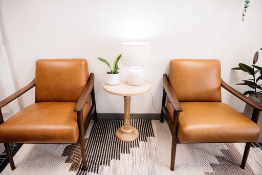 A high angle shot of brown chairs with white lamp and a house plant in a table in the living room