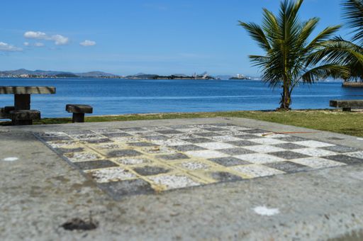 A chess table set up on a sandy beach with an ocean backdrop