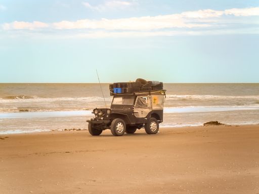 Going fishing in an old off road jeep on the sand of the beach.
