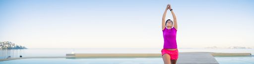 A panoramic shot of a Hispanic woman doing kundalini yoga by the sea in the morning