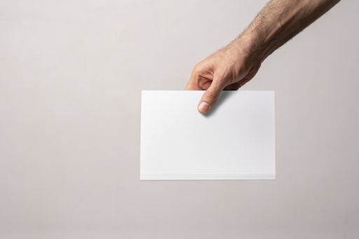 A male hand holding a closed book-catalog with a blank cover, mock-up series template ready for design