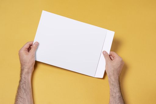 A male hand holding an A4 paper envelope, editable mock-up template for design