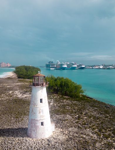This stunning image features a majestic white lighthouse surrounded by a tranquil turquoise sea and pristine sandy beach