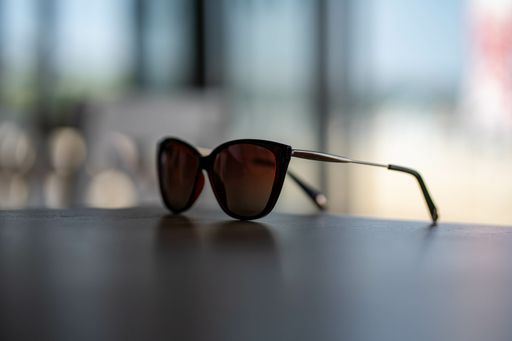 A closeup shot of brown wayfarer style sunglasses on a wooden table