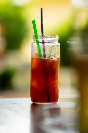 A dark stormy cocktail with ice cubes in a tall jar put outside on the table