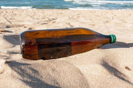 A closeup shot of a plastic bottle dumped on the beach