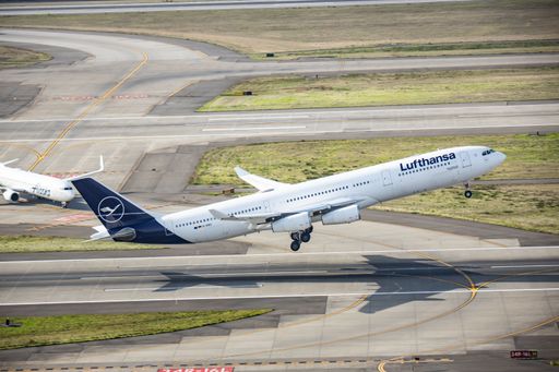 An Lufthansa aircraft takes off from an airstrip, its engines roaring as it ascends into the sky