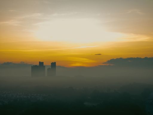 Aerial view of the golden sunrise near the neighbourhood in Malaysia with misty morning fog.