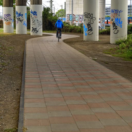 bicyclist driving between graffiti-sprayed bridge-columns during an overcast day