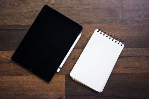 A top view of a wooden desk with notebooks and a pen.