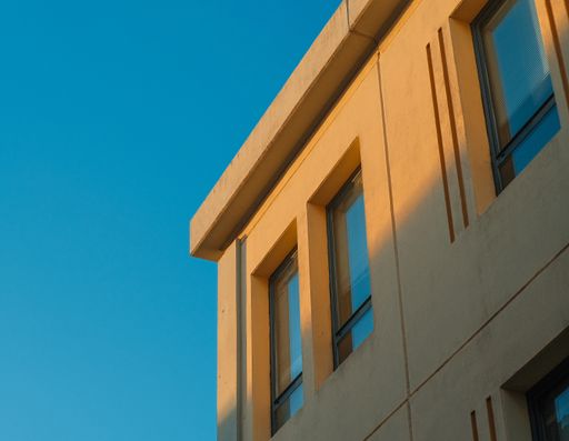 A closeup shot of a part of a building with closed windows against a blue sky background