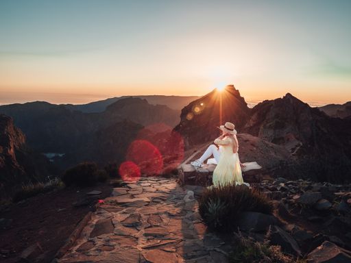 A blonde woman on a trail in the mountains, enjoying the beautiful view during sunset