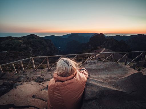 A blonde woman on a trail in the mountains, enjoying the beautiful view during sunset