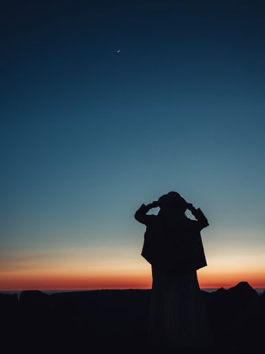 A silhouette of a female standing in the field and looking at a beautiful sunset