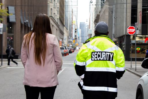 A closeup shot of a team of a security guard in uniform and a lady in suit patrolling the street