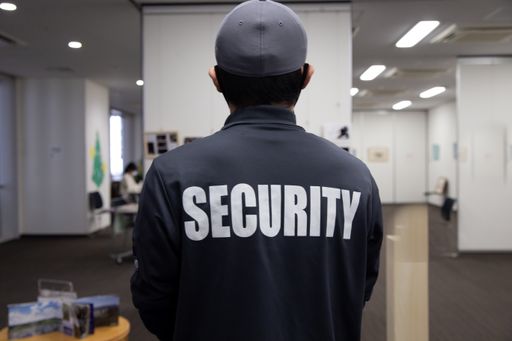 A rear view of a security guard in uniform patrolling in a commercial building