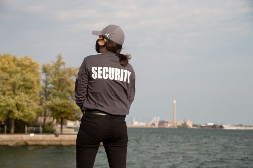 A female security guard in uniform and mask watching over the harbor area