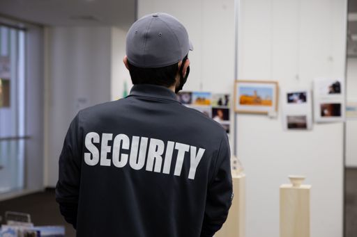 A rear view of a security guard in uniform patrolling in a commercial building