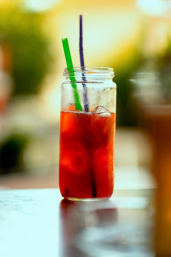 A vertical shot of a red cocktail on a tall clear glass on a wooden surface