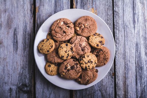 A closeup shot of chocolate chip cookies in a white plate on a wooden surface