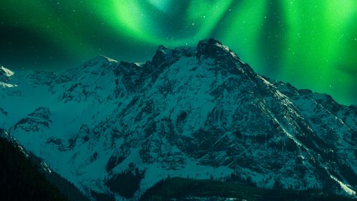 A breathtaking view of aurora borealis over a snow-covered mountain
