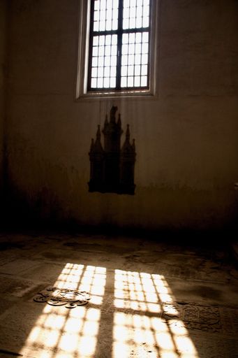 A vertical shot of a dark room with the sunlight passing through the window and lighting up the floor