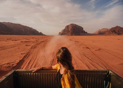 A young woman in a pick-up truck with a desert landscape in the background