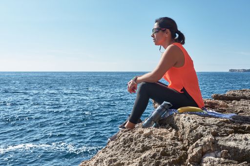 A Latin woman, middle-aged, resting, regaining strength, eating, drinking water, after a gym session, burning calories