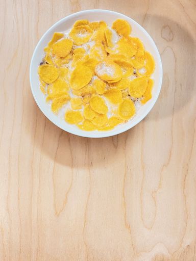 A top view of a bowl of cereal with milk on a wooden surface for a copy space
