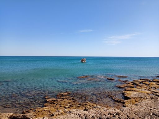 A natural view of rocky coast under a clear blue sky during summertime
