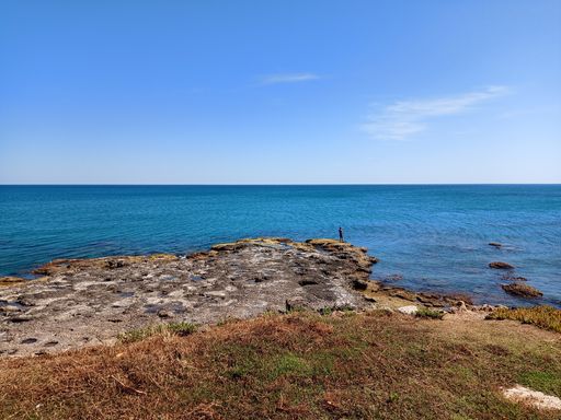 A natural view of rocky coast under a clear blue sky during summertime