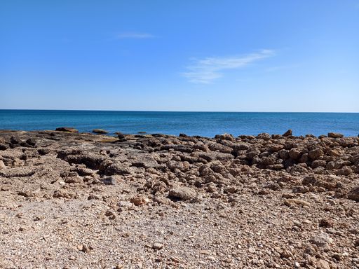 A natural view of rocky coast under a clear blue sky during summertime