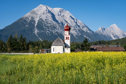 A majestic mountain range featuring a blanket of snow near the Church St. Magdalena in Leutasch