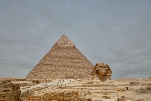 A majestic sphinx sculpture stands guard in front of the iconic pyramids of Giza, Egypt.