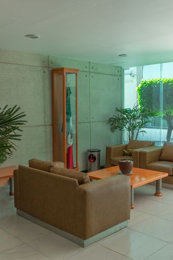 A vertical shot of comfortable coaches inside a waiting room of an office with the flag of Mexico