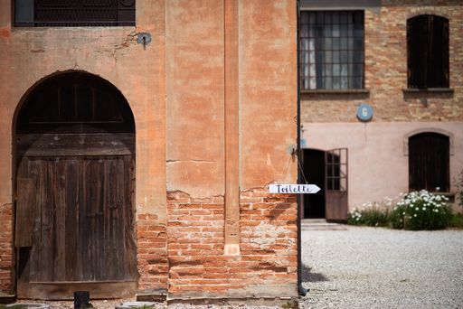 A scenic view of an old brick-walled building with signage pointing to a restroom