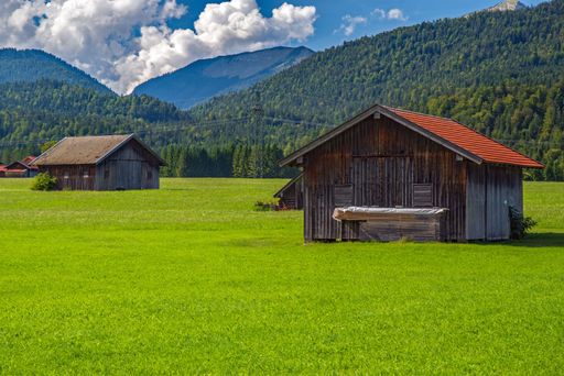 A scenic Alpine landscape with a green field and rural houses. Upper Bavaria, Germany