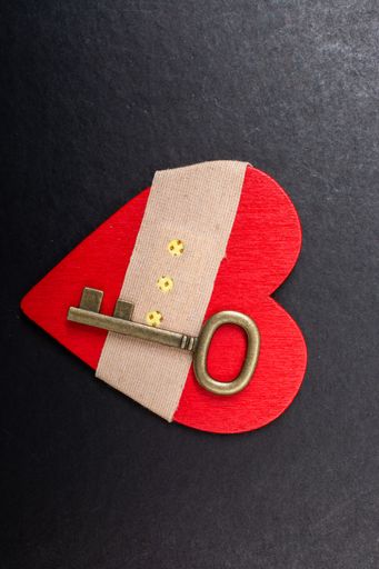 A top view of a key on a heart-shaped fabric wrapped with a patch