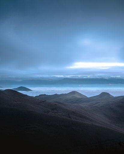 A mesmerizing view of the peak of the mountain and the clouds on a gloomy day