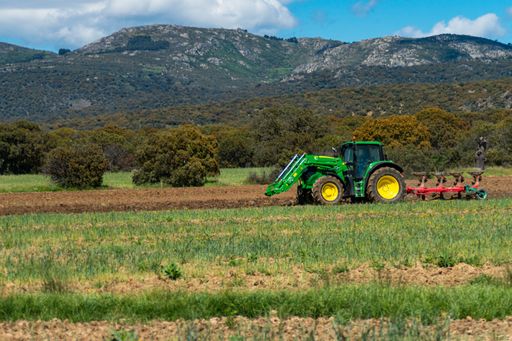 Tractor plowing the green field over a sky