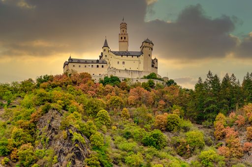 A low angle shot of Marksburg Castle on top of a hill with colorful trees in Braubach, Germany