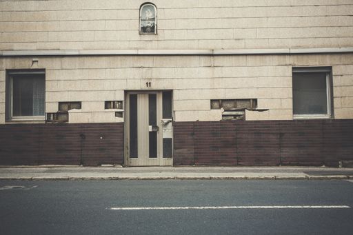 the facade of a beige and brown old building with defective walls near the asphalt road