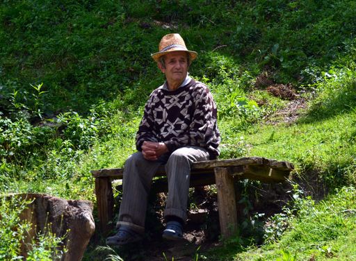 an old man sitting isolated on a bench in a rural area of Romania