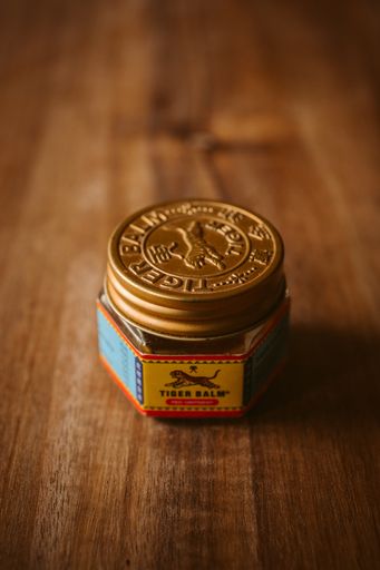 Tiger balm on wooden background, natural traditional ointment for relief muscle aches.