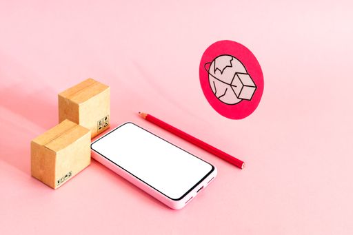 A smartphone with a blank screen with cardboard boxes on pink background - online shopping and global delivery service