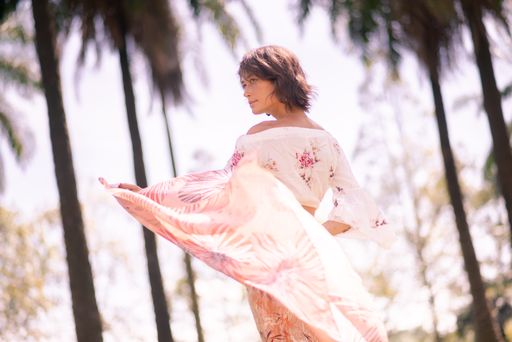 A shallow focus shot of a Caucasian female traveler alone amidst palm trees in Putrajaya, Malaysia