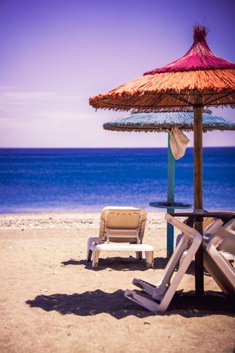 A vertical of comfortable beach lounge chairs against the sea